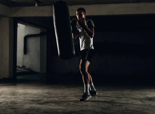 Male boxer as exercise for the big fight. Boxer hits punching bag. Young masculine male athlete