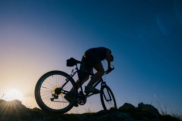 Silhouette di un mountain bike in sella alla sua mountain bike su — Foto Stock