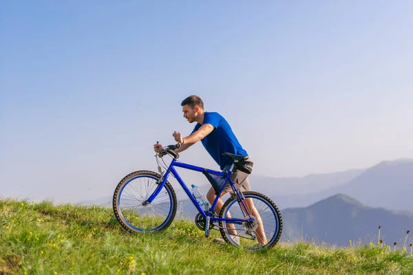 累坏了的山地自行车手把自行车推上了山顶 — 图库照片