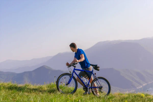 累坏了的山地自行车手把自行车推上了山顶 — 图库照片