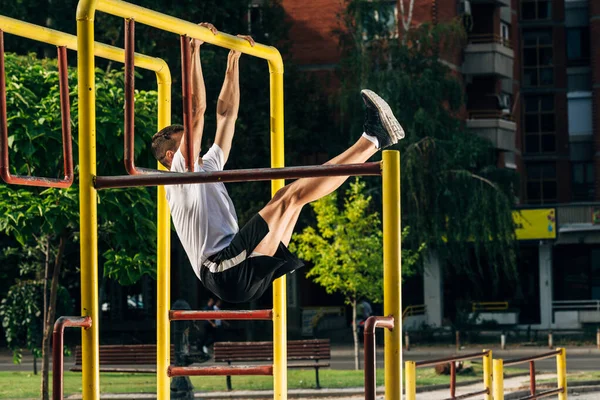 Atlético hombre deportivo haciendo pull ups en el gimnasio al aire libre —  Fotos de Stock