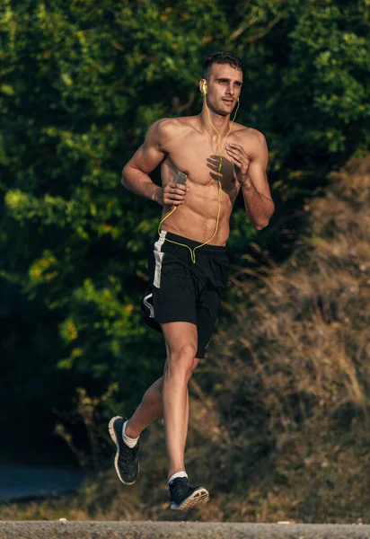 Running man met mobiele training tijdens het luisteren naar muziek op headph — Stockfoto