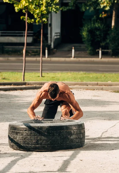 Sportsman förbereda sig för att lyfta däck under cross träning inom idrott — Stockfoto