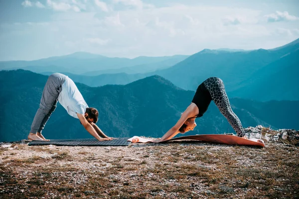 Pareja joven está practicando yoga en el lago de montaña — Foto de Stock