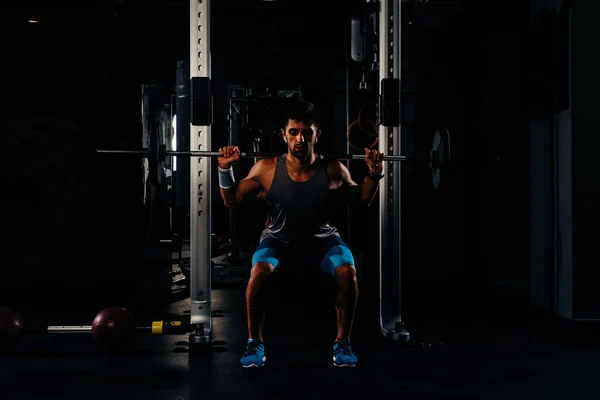 Slim hombre muscular haciendo ejercicio con pesas en el gimnasio —  Fotos de Stock