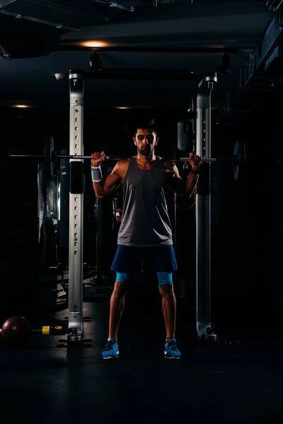 Karcsú izmos férfi edz súlyokkal a tornateremben — Stock Fotó
