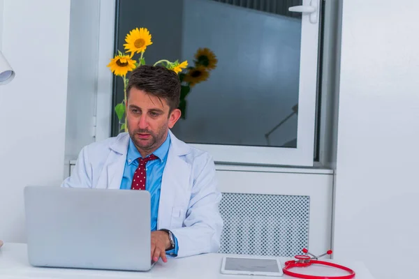 Hombre grave caucásico médico sentado en su oficina solo y th —  Fotos de Stock