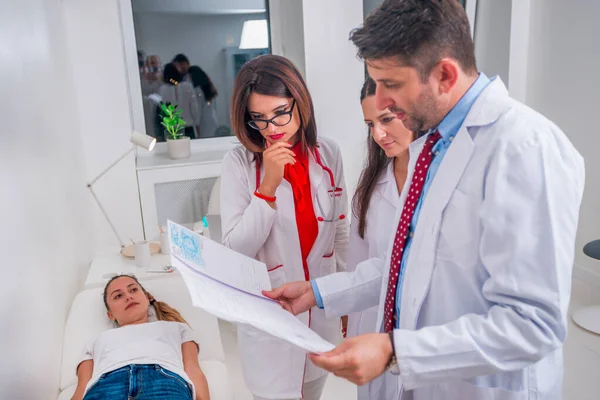 Gruppe von Ärzten steht neben einem kranken Patienten und diskutiert — Stockfoto