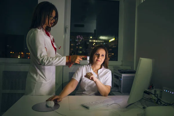 Médicos femeninos (médicos) trabajan en una PC tarde en la noche . —  Fotos de Stock