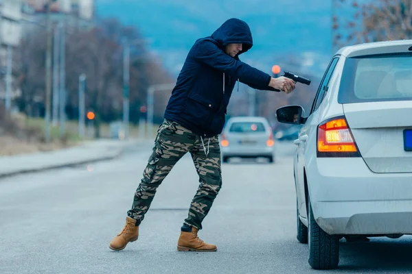 Gangster avec un pistolet essayant de voler un gars qui est assis dans son — Photo