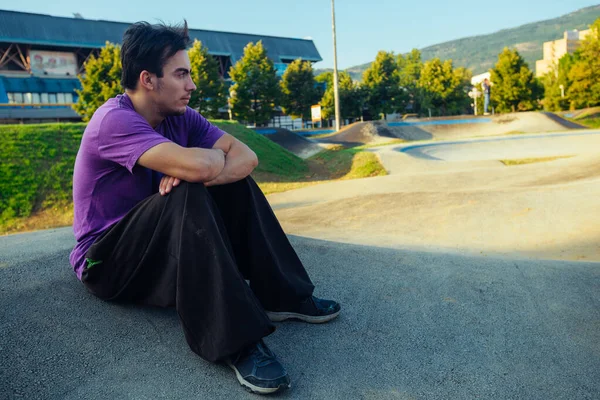 Young guy sitting at the skatepark — Stock Photo, Image
