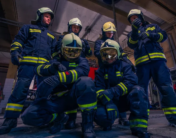 Портрет группы пожарных перед пожарной машиной внутри здания — стоковое фото
