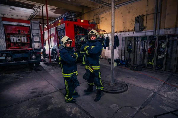 Bomberos que preparan su uniforme y el camión de bomberos de la ba —  Fotos de Stock