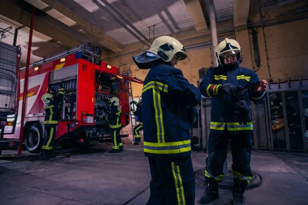 Bomberos que preparan su uniforme y el camión de bomberos de la ba —  Fotos de Stock