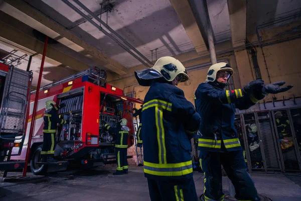 Bomberos que preparan su uniforme y el camión de bomberos de la ba —  Fotos de Stock