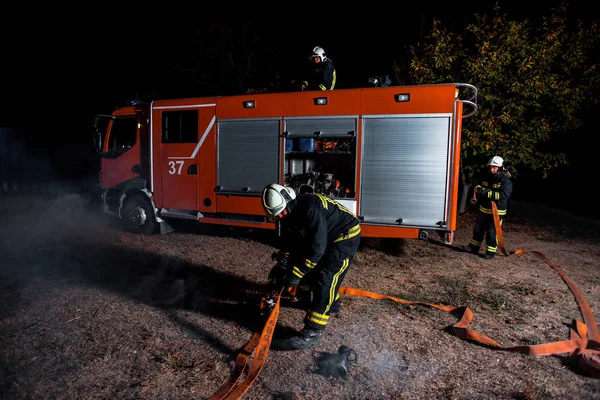 Strażacy Rozpalający Ogień Pomocą Węża Wodnego Podłączonego Wozu Strażackiego — Zdjęcie stockowe