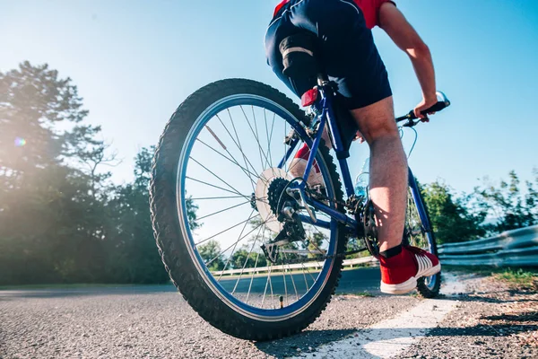 Fit male biker cyclist riding his bike cycle on an asphalt road — ストック写真