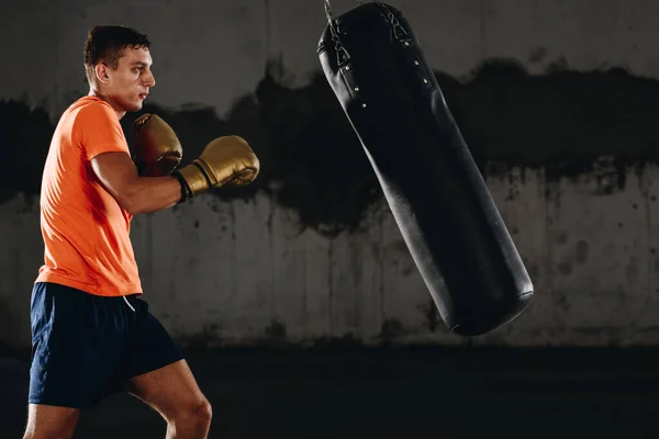 年轻男子运动员在黑暗背景下的健身馆进行拳击锻炼 运动员努力训练 踢拳的概念 — 图库照片