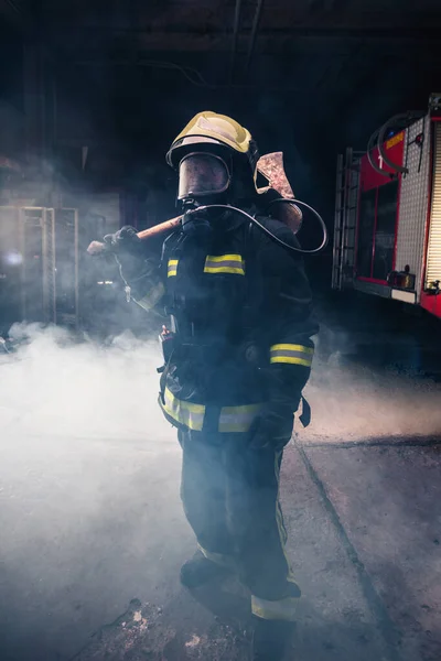 Retrato de una mujer bombero mientras sostiene un hacha y el desgaste — Foto de Stock