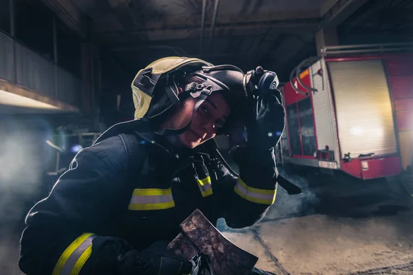 Retrato de una mujer bombero mientras sostiene un hacha y el desgaste —  Fotos de Stock
