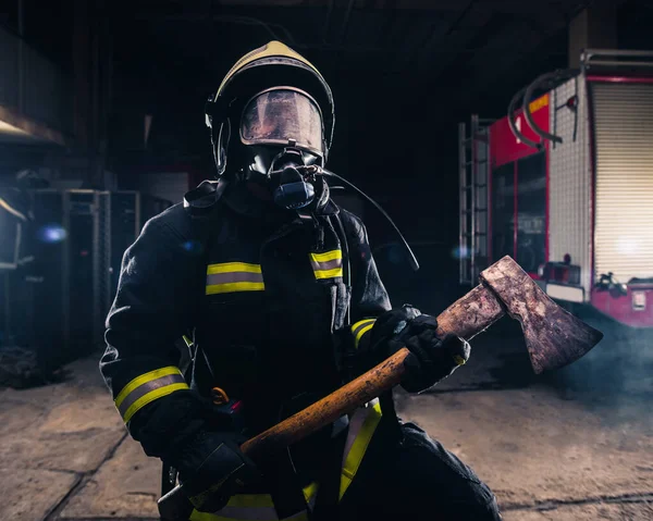 Retrato de una mujer bombero mientras sostiene un hacha y el desgaste — Foto de Stock