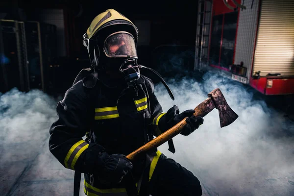 Portrait of a female firefighter while holding an axe and wearin