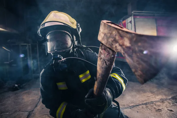 Portrait of a female firefighter while holding an axe and wearin — Stock Photo, Image