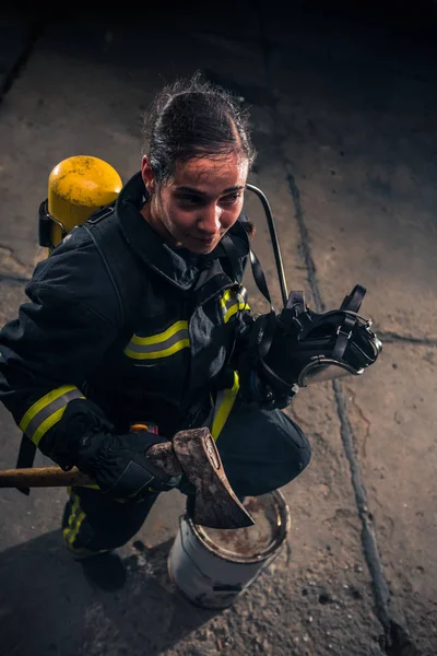 一名女消防员手持斧头 戴着氧气面罩 被烟雾笼罩在室内的画像 — 图库照片