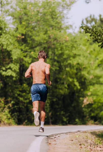 男は山の中で道路に発芽しながらジョギング — ストック写真