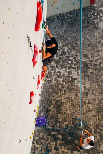 Uomo muscolare arrampicata su una grande parete — Foto Stock