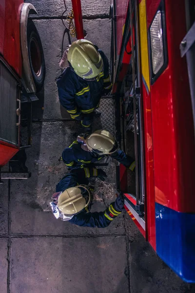 Пожежники перевіряють пожежний двигун всередині пожежного відділення з — стокове фото