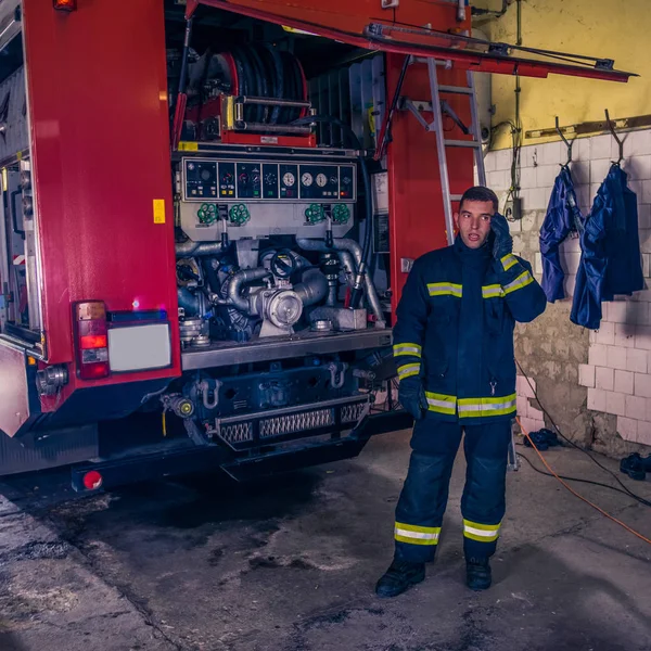 Um bombeiro reparando o motor de incêndio na estação de incêndio — Fotografia de Stock