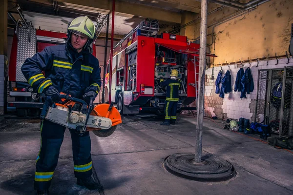 Πυροσβέστης με στολή και κράνος που κρατάει αλυσοπρίονο με φωτιά — Φωτογραφία Αρχείου