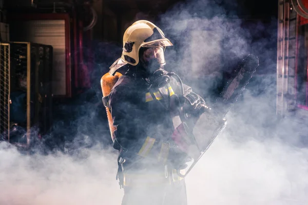 Retrato del joven bombero de pie y celebración de un chaleco en el —  Fotos de Stock