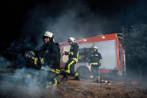 Equipe de combate a incêndios em uma cena de incêndio — Fotografia de Stock