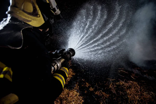 ヘルメットと酸素マスクを持つ消防士が燃える火を出す — ストック写真