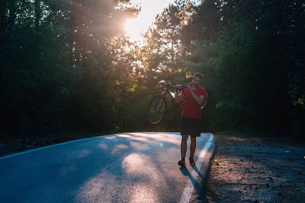 Silný atlet cyklista (cyklista) nesoucí své kolo na svém batohu — Stock fotografie