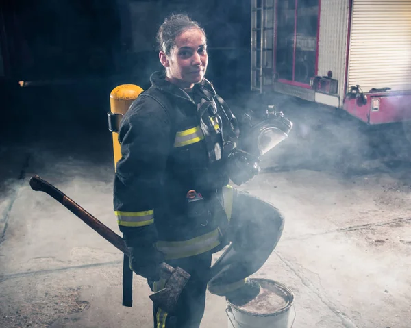 Retrato de uma mulher bombeira segurando um machado e vestindo — Fotografia de Stock