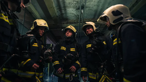 Equipe de bombeiros de pé dentro (dentro) um buliding próximo — Fotografia de Stock