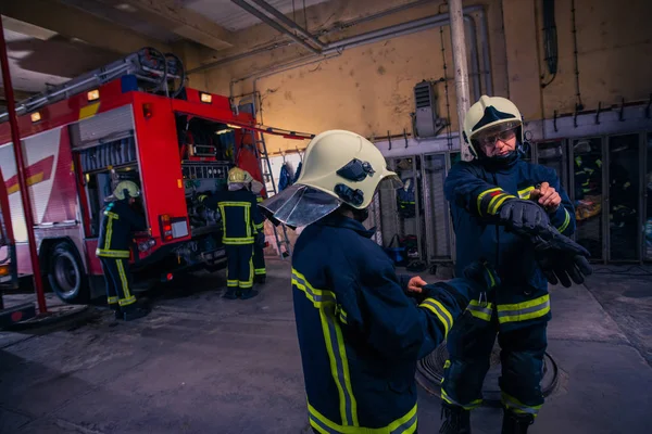 Bomberos que preparan su uniforme y el camión de bomberos de la ba —  Fotos de Stock