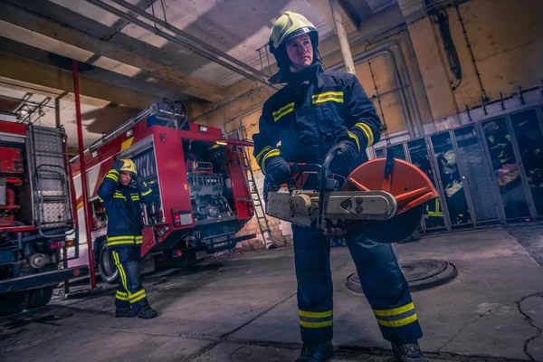 Un bombero con uniforme y casco que sostiene un chaleco con fuego. —  Fotos de Stock