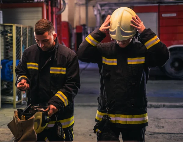 Portrét dvou mladých hasičů v uniformě stojících uvnitř jedle — Stock fotografie