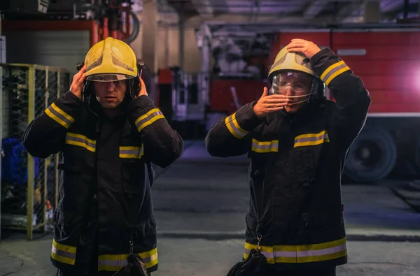 Retrato de dos jóvenes bomberos de pie uniforme en el interior del abeto —  Fotos de Stock