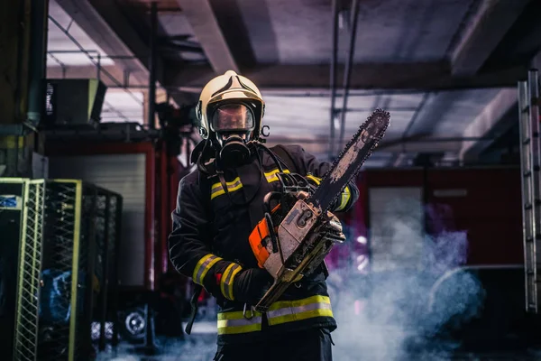 Portrait d'un jeune pompier debout tenant une scie à chaîne — Photo
