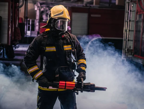 Портрет молодого пожежника, що стоїть і тримає бензопилу в — стокове фото