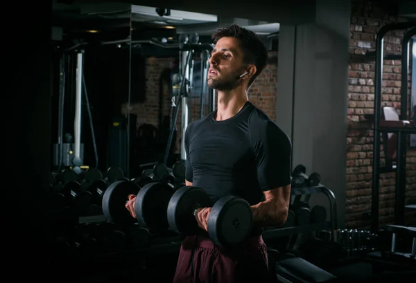 Slim musculoso hombre levantando pesas en el gimnasio — Foto de Stock