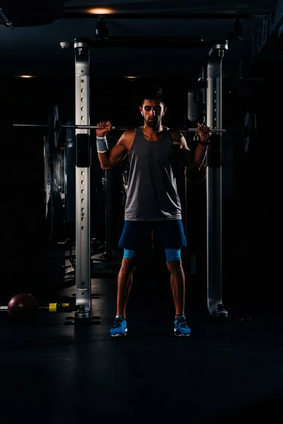 Karcsú izmos férfi edz súlyokkal a tornateremben — Stock Fotó