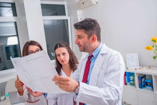 Gruppe von Ärzten steht neben einem kranken Patienten und diskutiert — Stockfoto