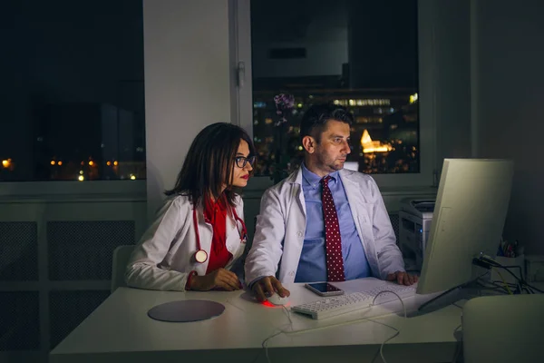 Los médicos trabajan en la oficina por la noche en una PC (computadora  ) —  Fotos de Stock