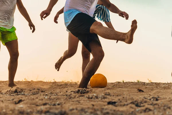 Группа друзей играет в футбол на пляже — стоковое фото
